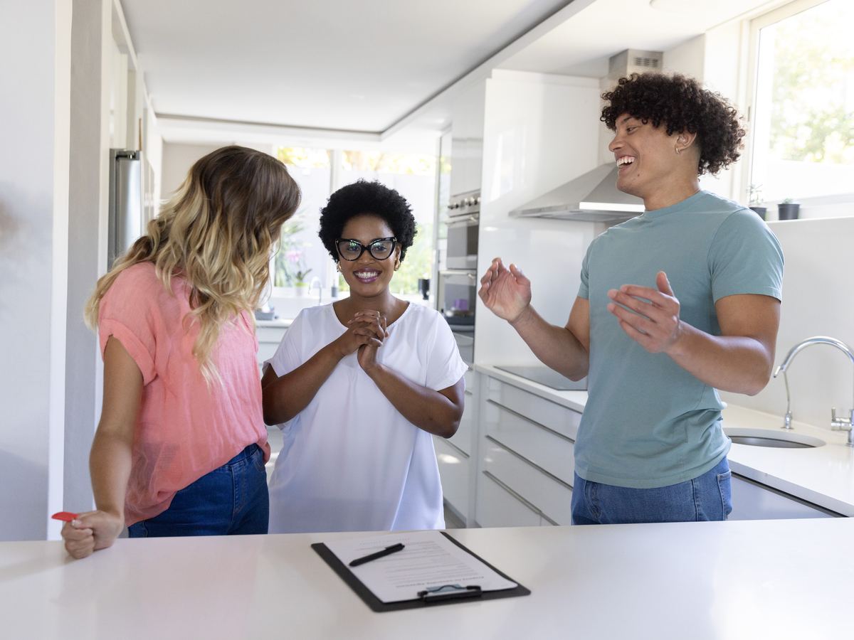 Three housemates talking in a bright kitchen